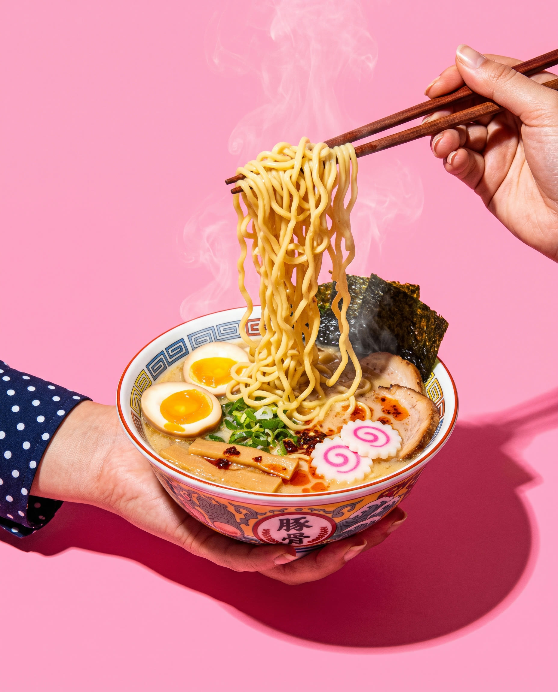 Chopsticks pulling a tangle of wavy ramen noodles out of a steaming tonkotsu bowl